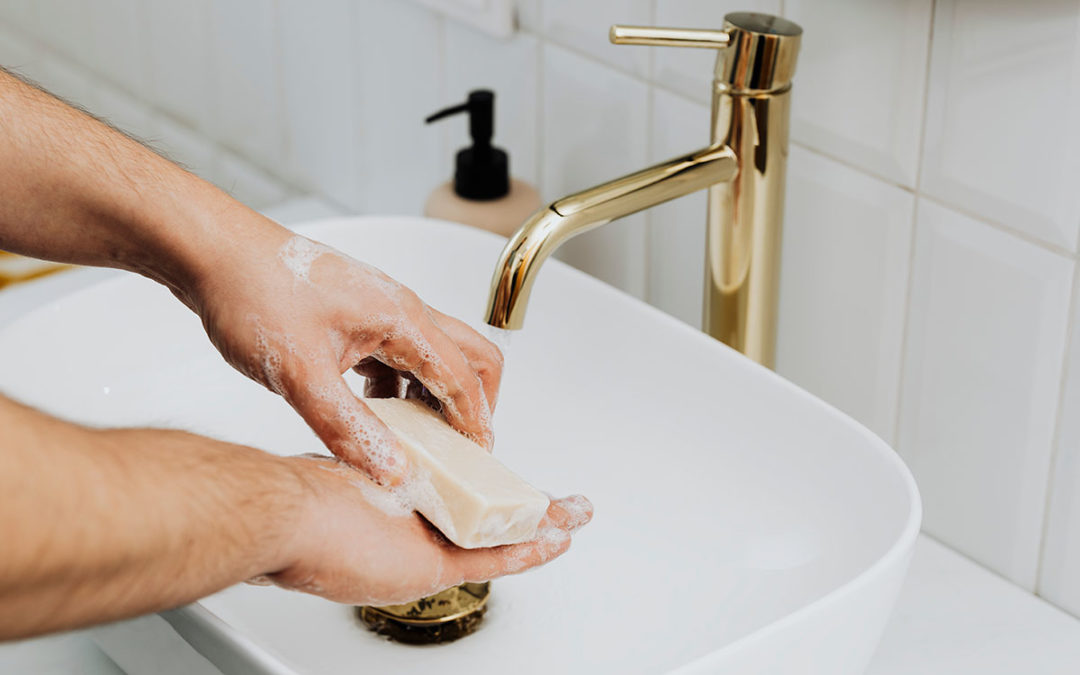 Hombre lava sus manos con una pastilla de jabón sólido en un lavabo